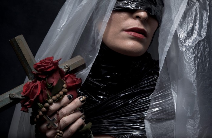 Woman in plastic wrap holding a cross and roses