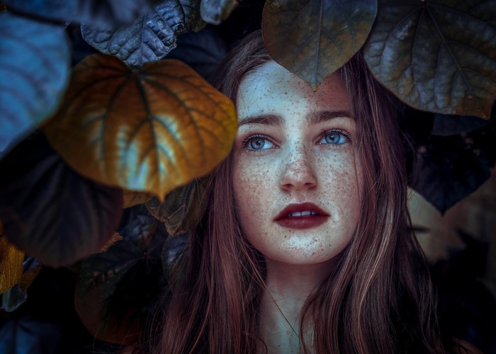 Woman with freckles surrounded by leaves