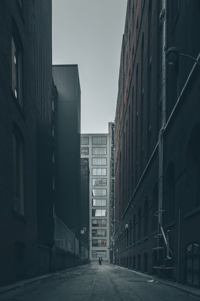 Alleyway between brick buildings with a lone figure walking