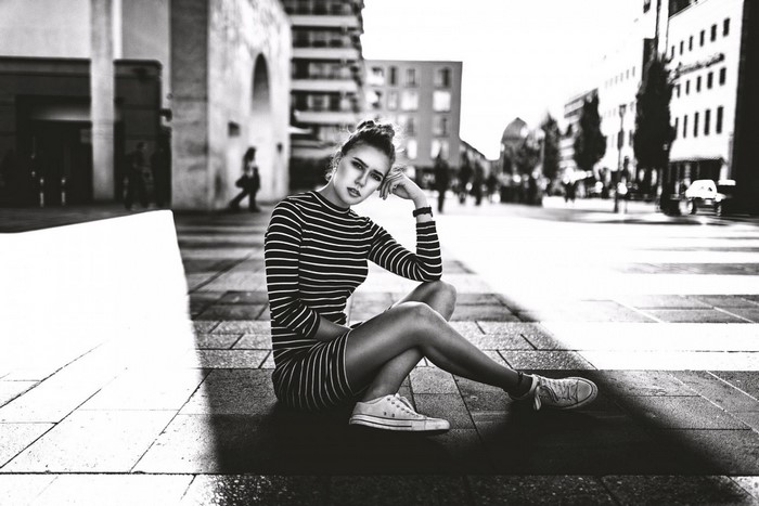 Monochrome street portrait of a woman sitting on the ground