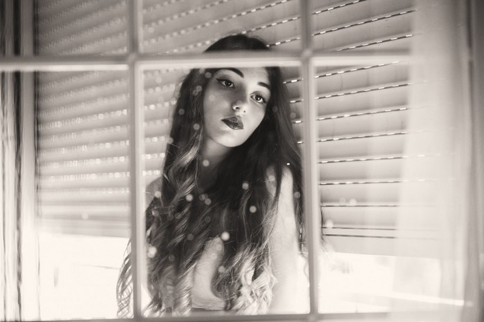 Monochrome portrait of a woman behind a window
