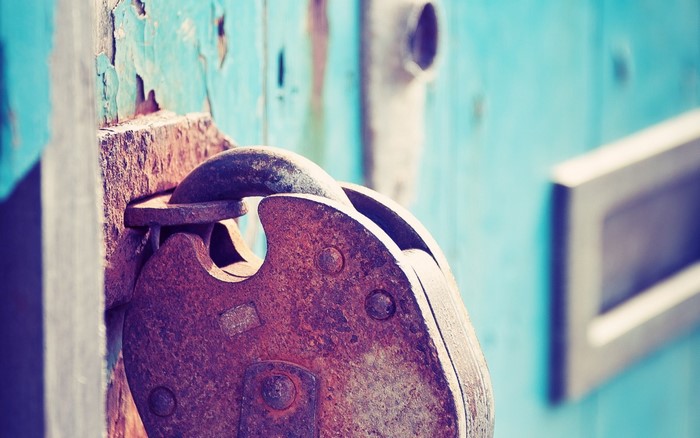 Close up of a rusty padlock on a blue door