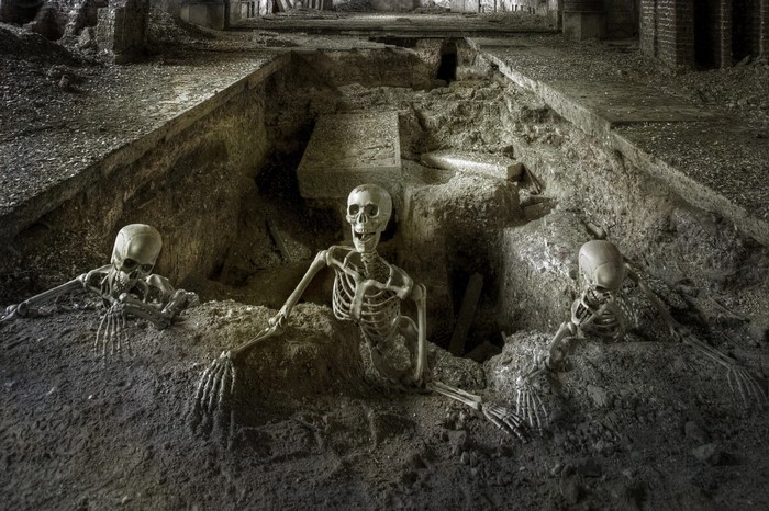 Three skeletons emerging from a pit in ancient ruins