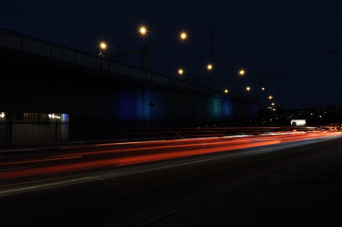 Night highway with light trails under a bridge