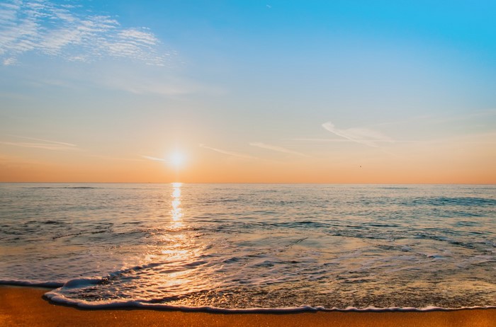 Sunrise over the ocean with waves on the shore