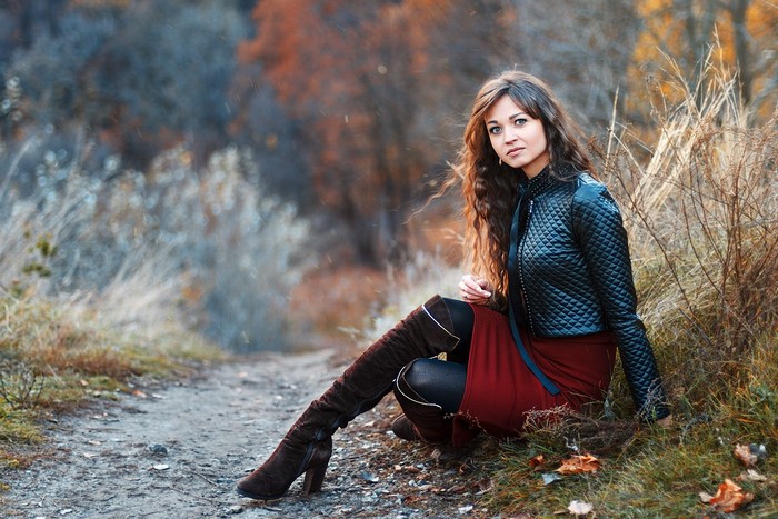 Woman in black jacket and maroon skirt in autumn forest