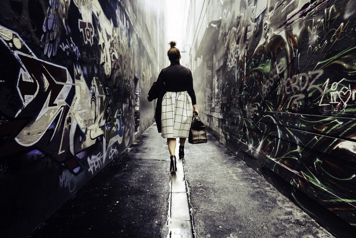 Woman walking down a graffiti-covered alley