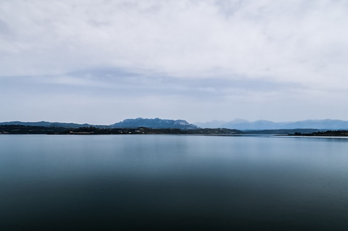 Calm lake with distant mountains under a cloudy sky