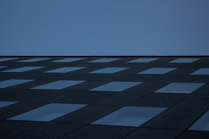 Modern building facade with repeating windows against blue sky