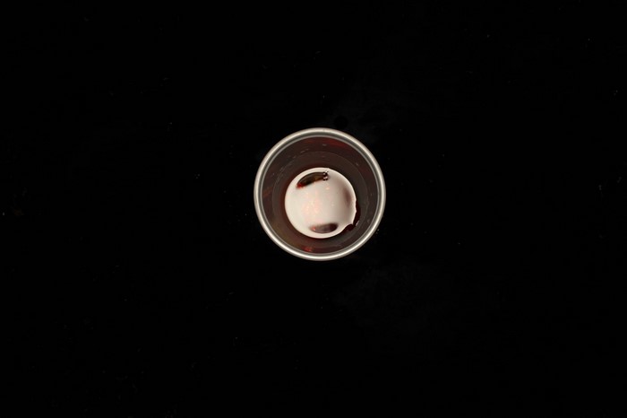 A small cup with red liquid and reflections