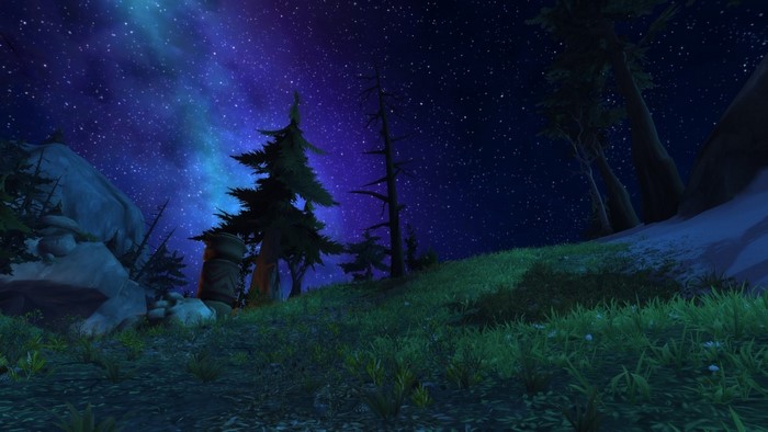 Night sky over a grassy hill with trees in World of Warcraft