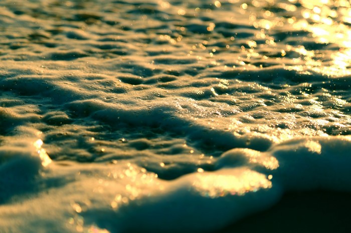 Sunlight reflecting on sea foam and waves at sunset