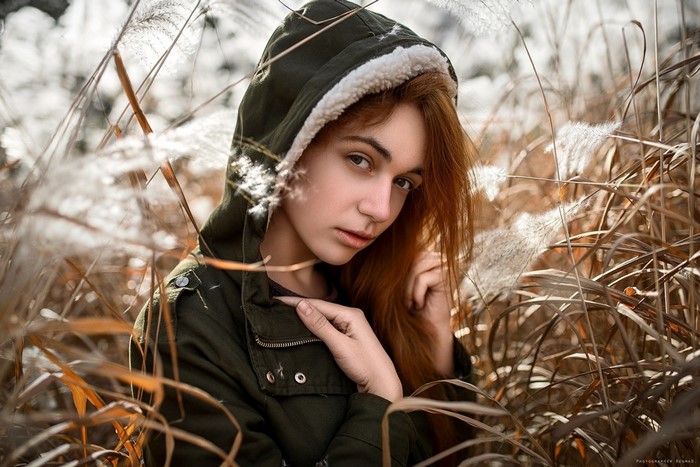 Woman in a hooded jacket in tall grass