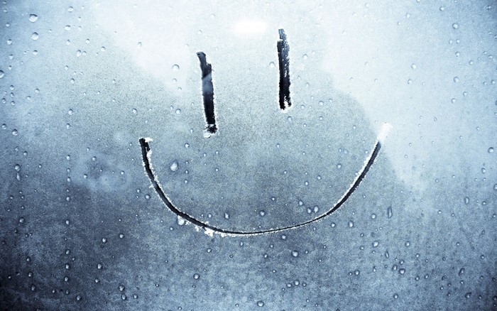 Smiley face drawn on a wet, frosted window