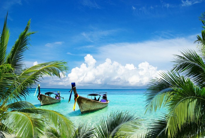 Tropical beach with longtail boats and palm trees