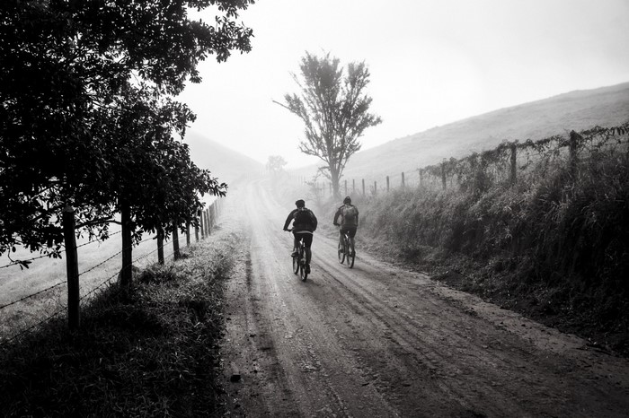 Two people cycling on a misty rural road