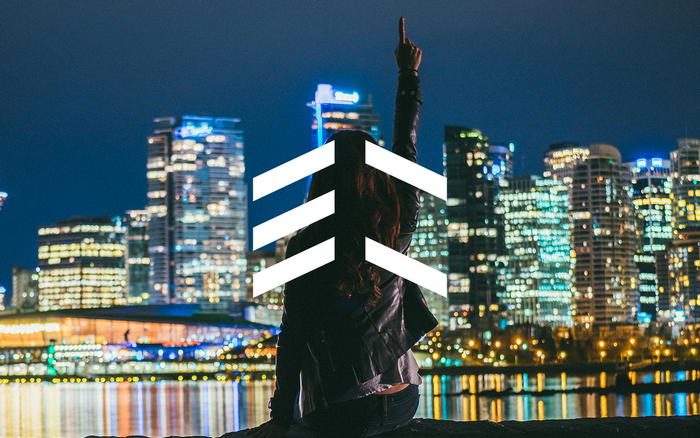 Woman pointing up in front of city skyline at night