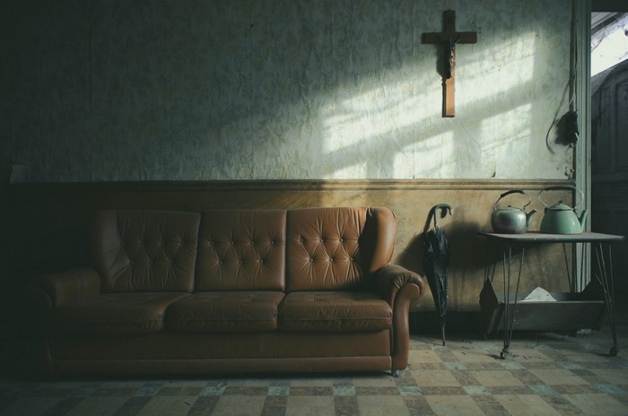 Abandoned room with couch, cross, and kettles
