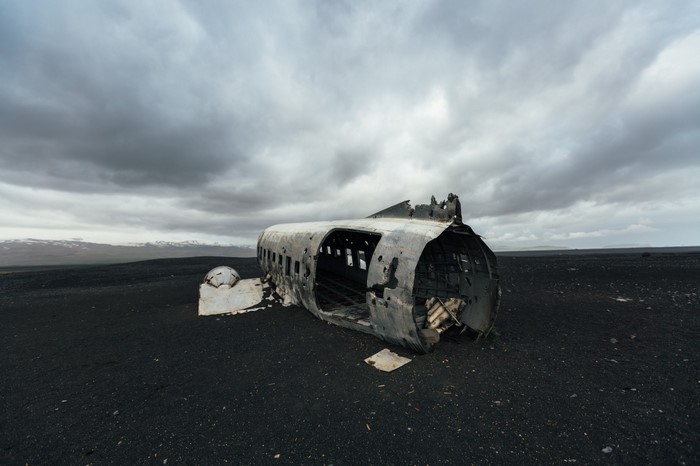 Wreckage of a plane on a black sand beach