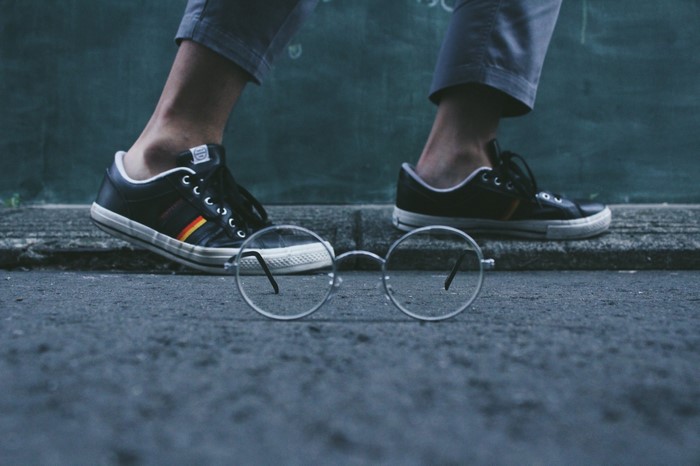 Person wearing sneakers and glasses on pavement