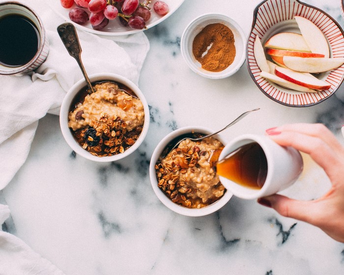 Overhead view of breakfast with oatmeal, grapes, and apples