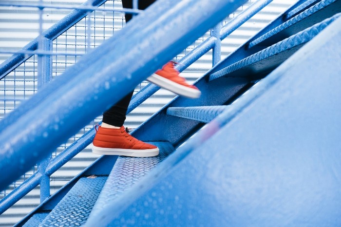 Person in red shoes climbing blue stairs