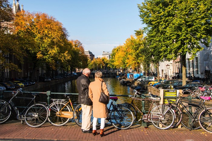 Couple on a bridge in Amsterdam with bicycles and autumn trees