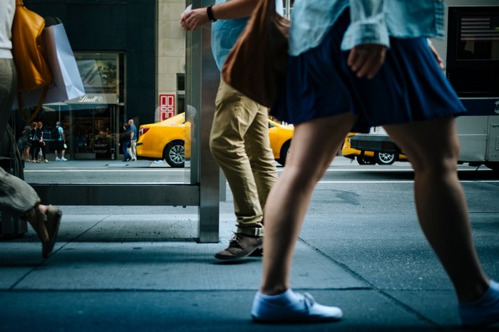 People walking on a city street with a yellow taxi
