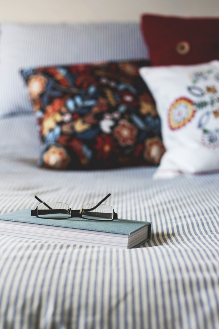 Glasses on a book on a striped bed