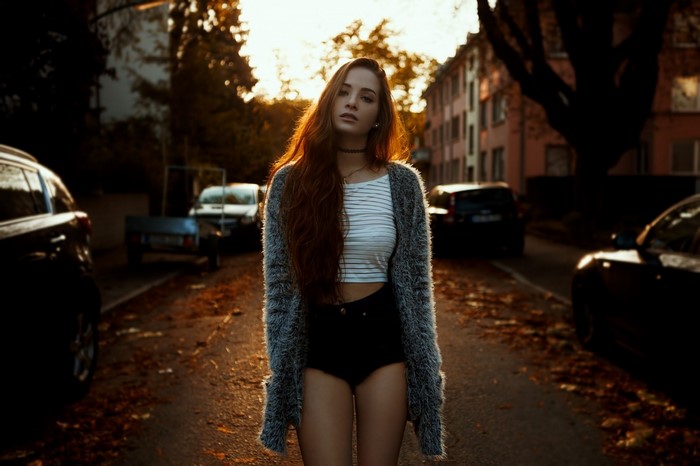 Woman in sweater and shorts on street at sunset