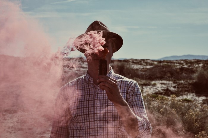 Man in hat holding pink smoke bomb