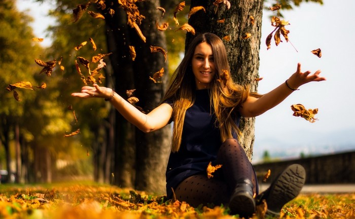Woman throwing leaves in the fall