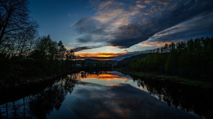 River reflecting sunset clouds and trees at dusk