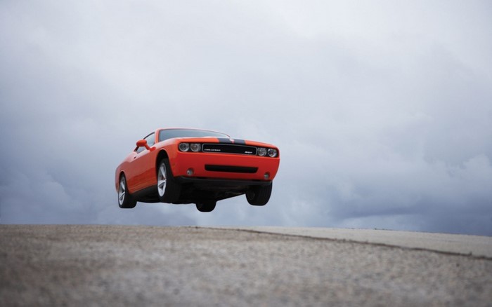 Orange Dodge Challenger SRT8 jumping over a road