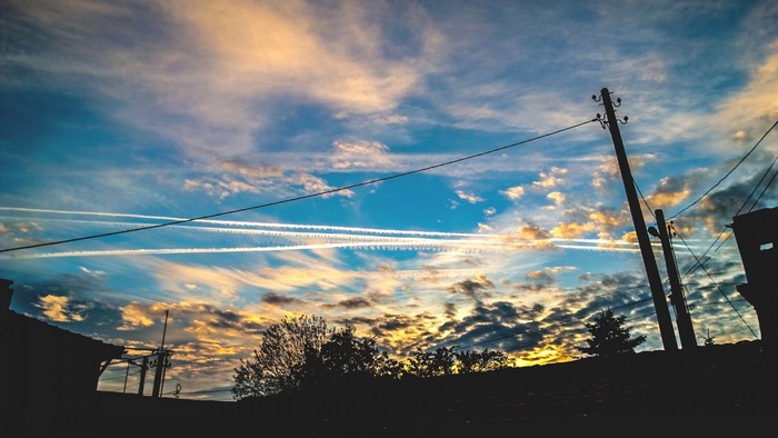Sunset sky with contrails and utility poles