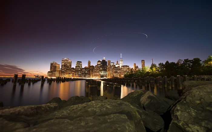 New York City skyline at dusk with water and rocks