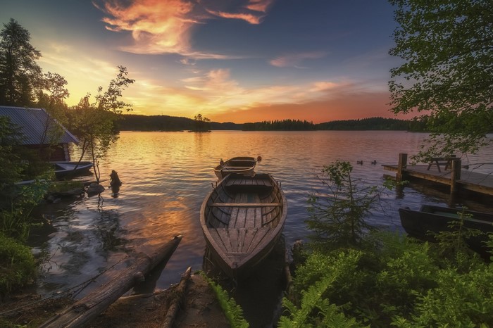 Wooden boats on a lake at sunset with a boathouse