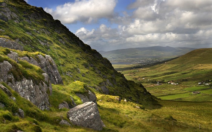 Green valley with rocky hillside and distant mountains