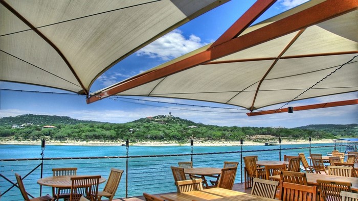 Outdoor restaurant seating with lake and hill view