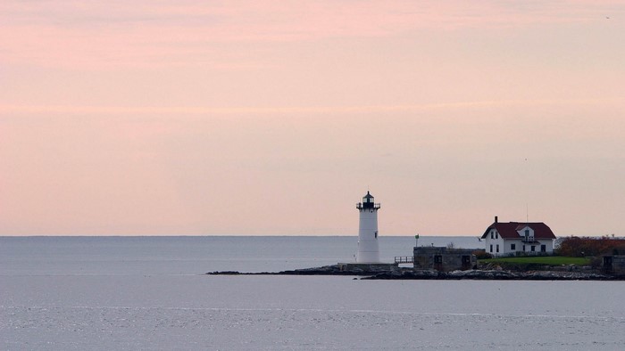 Lighthouse and house on a rocky shore at dusk