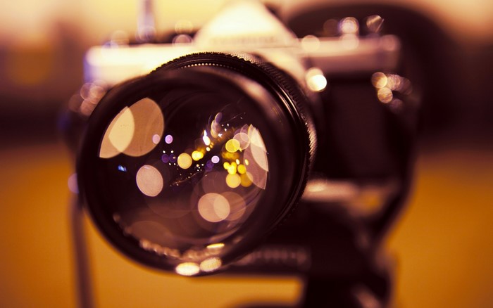 Close-up of a camera lens with bokeh lights