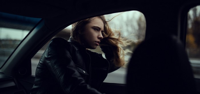 Woman in leather jacket looking out car window