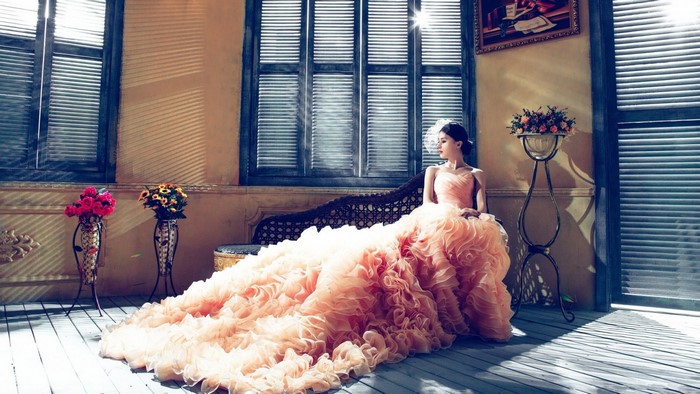 Woman in a peach ruffled dress sitting indoors