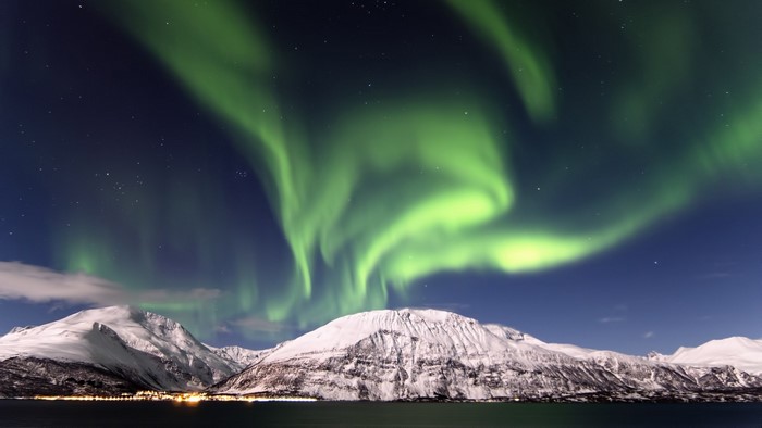 Aurora Borealis over snow-covered mountains and a lake