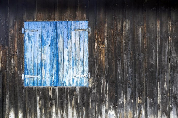 Weathered wooden wall with blue shutters