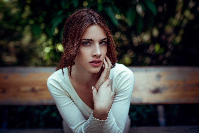 Woman with brown hair sitting on a bench