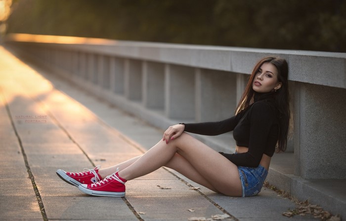 Woman Sitting at Sunset Wearing Red Sneakers