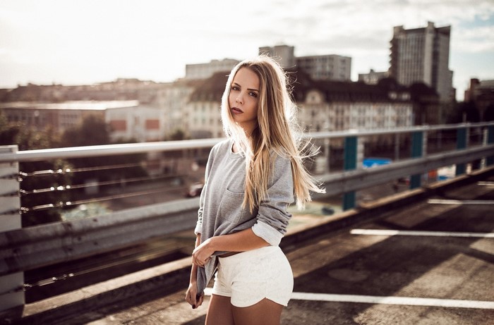 Woman in grey sweatshirt and white shorts on a rooftop