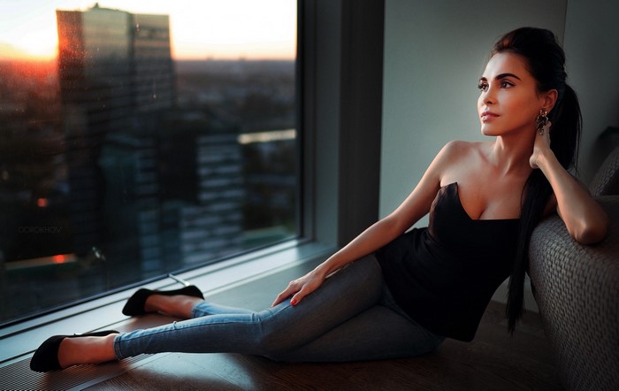Woman in black top and jeans by the window