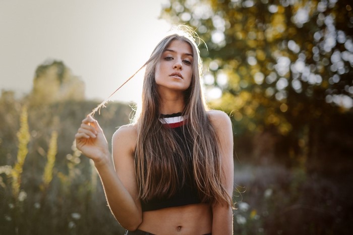 Woman with long brown hair in a black crop top outdoors